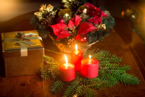 Imagen de primer plano de la quema de velas de Navidad en la mesa junto al regalo — Foto de Stock