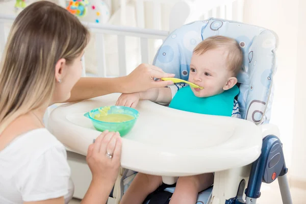 Potret bayi duduk di kursi tinggi dan makan bubur — Stok Foto