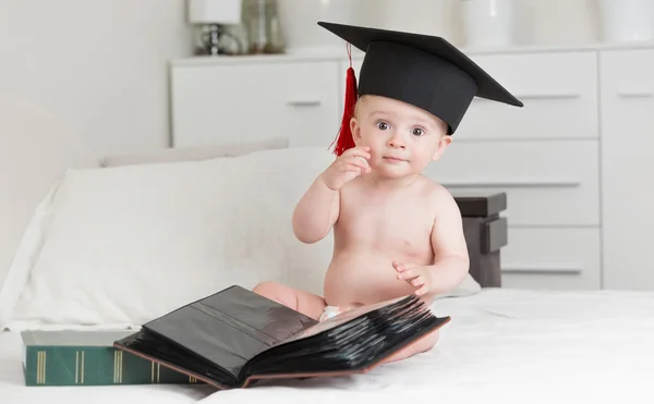 Retrato de bebé inteligente en gorra de graduación posando con libros — Foto de Stock