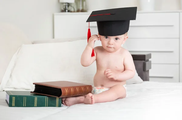 10 meses de idade menino sentado na cama com livros e decolando g — Fotografia de Stock