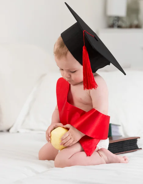 Retrato de lindo bebé en gorra de graduación sosteniendo manzana. Concepto o — Foto de Stock