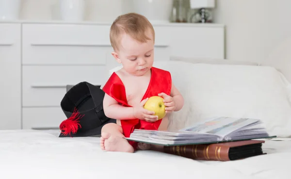 Bebê na formatura cap e fita segurando maçã e leitura grande — Fotografia de Stock