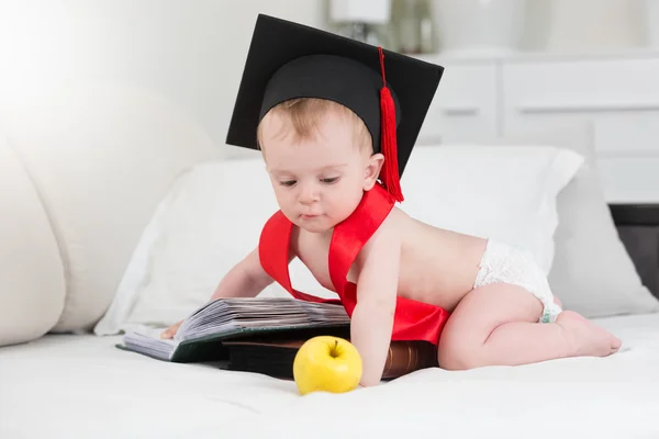 Baby boy kalappal pózol az apple és a nagy könyv — Stock Fotó