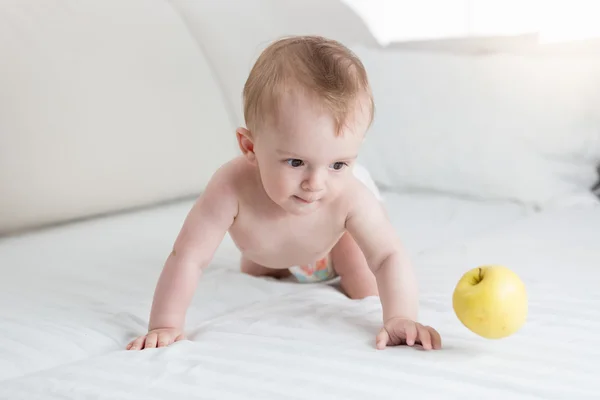Mignon bébé de 10 mois jouant avec la pomme jaune sur le lit — Photo