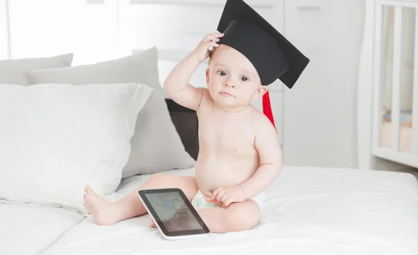 Niño de 10 meses en gorra de graduación sentado con digital ta —  Fotos de Stock