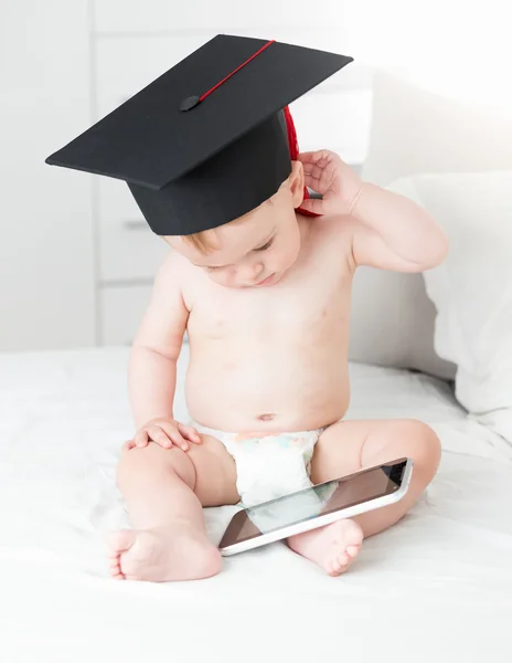 Bambino adorabile con cappuccio graduato e tablet digitale. C — Foto Stock