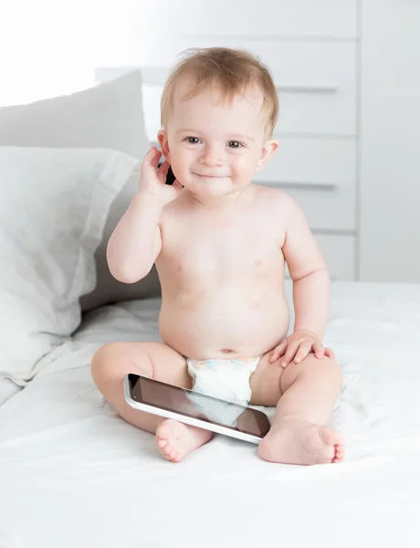 Portrait of smiling baby sitting on sofa and holding digital tab — Stock Photo, Image