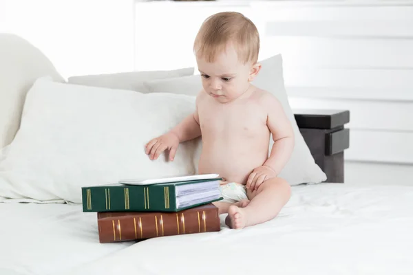 Bambino adorabile utilizzando tavolo digitale sdraiato su pila di libri. Conce — Foto Stock