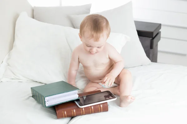 10 månader gammal baby sitter bredvid trave böcker och använda digi — Stockfoto