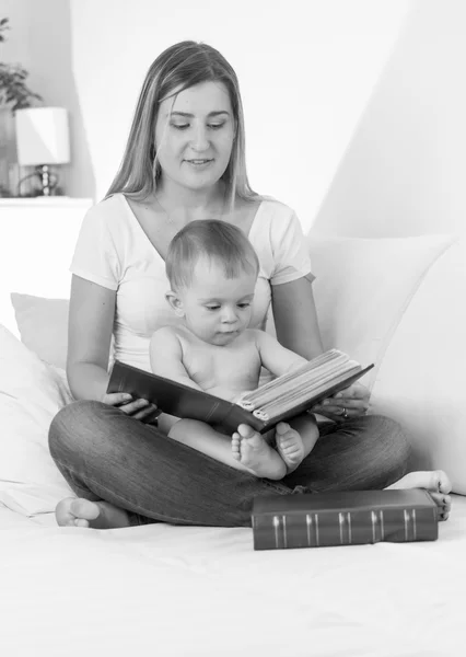 Portrait noir et blanc de mère souriante lisant le livre à son b — Photo