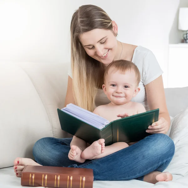 Bela mãe lendo grande livro para seu menino sorridente — Fotografia de Stock