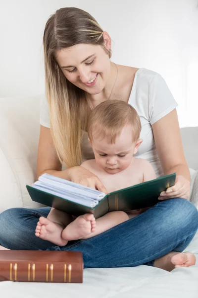 Sonriente madre y su niño de 9 meses sentado en el sofá y —  Fotos de Stock