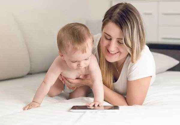 Getinte portret van lachende moeder met baby spelen op tablet com — Stockfoto