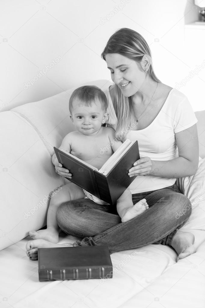 Black and white image of smiling mother looking at photos in alb