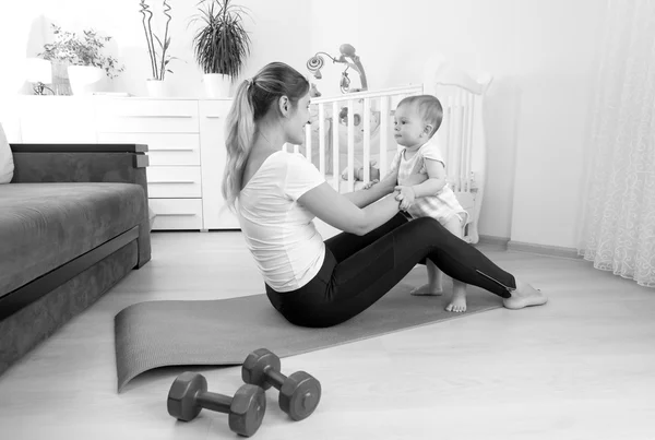 Imagen en blanco y negro de madre feliz ejercitándose en el suelo con h — Foto de Stock