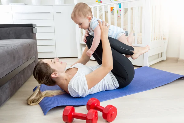 Matka z dzieckiem robi joga ćwiczenia na podłodze w pokoju dziennym — Zdjęcie stockowe