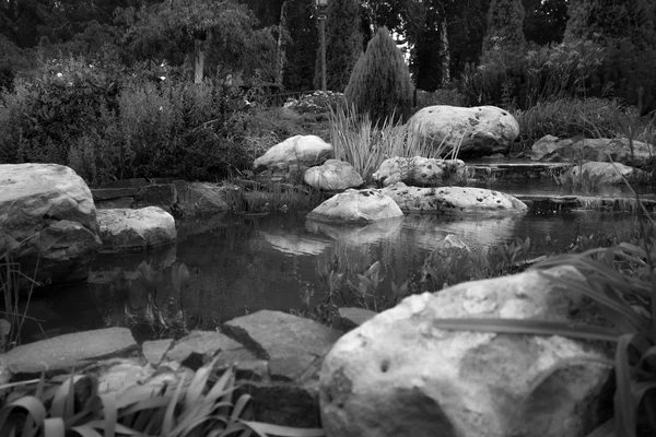 Black and white image of beautiful pond with big boulders in gar — Stock Photo, Image