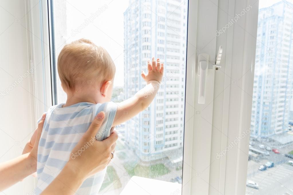 Closeup of mother holding baby boy while he is looking outside t