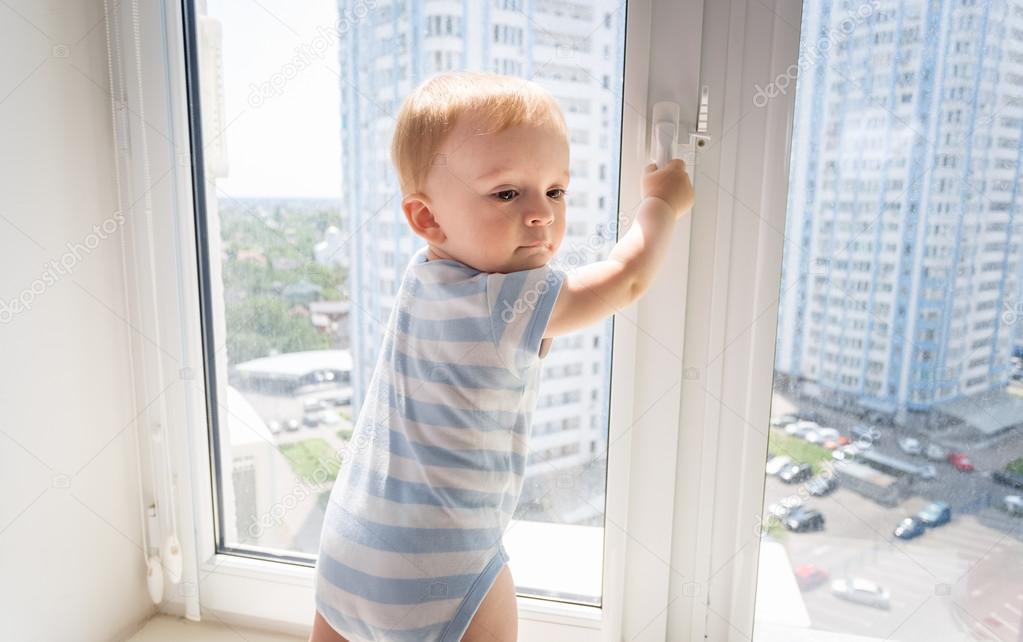 Portrait of 10 months old baby trying to open window