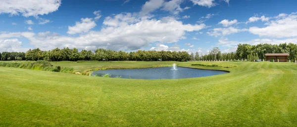 Panorama z golfového hřiště s rybníkem ve slunečný den — Stock fotografie