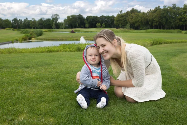 Niño de 9 meses sentado en la hierba en el parque con su beautifu — Foto de Stock