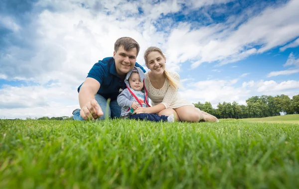 9 aylık bebek çocuk çimenlerin üzerinde rahatlatıcı ile mutlu genç aile — Stok fotoğraf