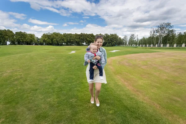 Lachende vrouw houdt van vrolijke jongetje en hebbend pret op gras — Stockfoto
