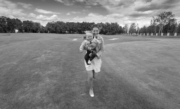 Black and white image of happy mother running on grass at park w — Stock Photo, Image