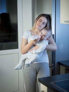 Uykulu anne beslenme bebek oğlundan kitche şişesinde portresi