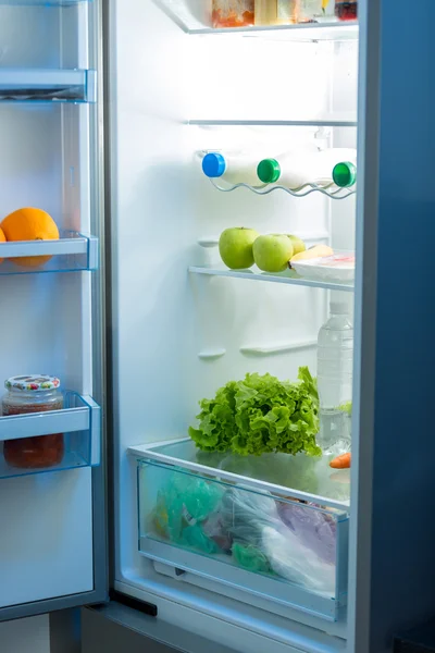 Open refrigerator full of food on kitchen — Stock Photo, Image