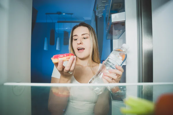 Beautiful woman choosing between late supper or drinking water. — Stock Photo, Image