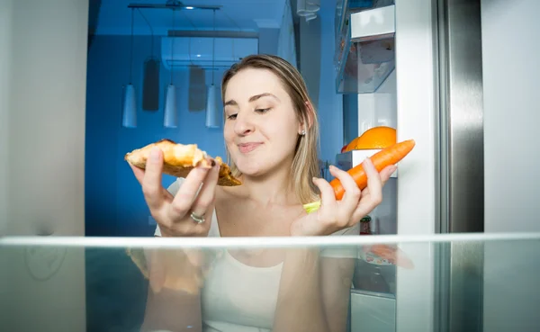 Portrait of woman choosing between healthy carrot and unhealthy — Stock Photo, Image