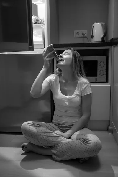 Foto en blanco y negro de una mujer hambrienta comiendo pizza en la cocina fl — Foto de Stock