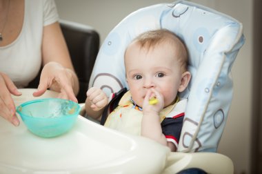 Yemek sandalyesi oturan bebek oğlu vererek anne