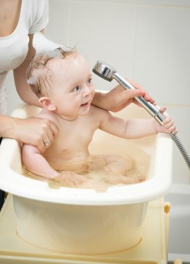 Neşeli bebek çocuk banyo duş başlığı ile oynarken