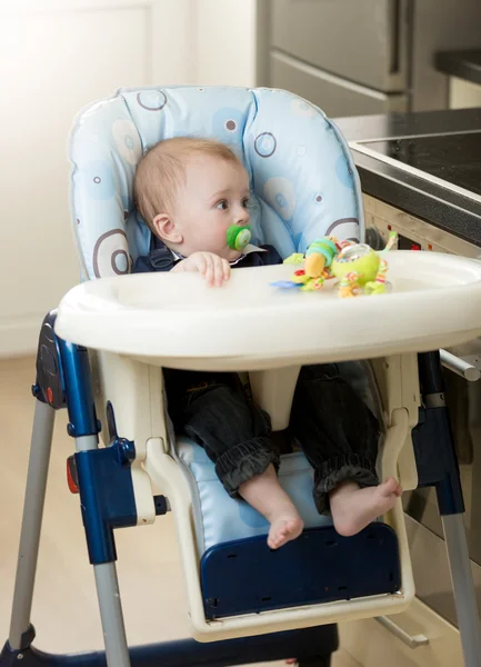 Мальчик 0 месяцев, сидящий в детском стульчике — стоковое фото