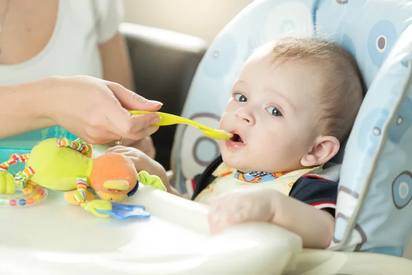 Portrait of cute adorably baby boy sitting in chair and eating f — Stock Photo, Image