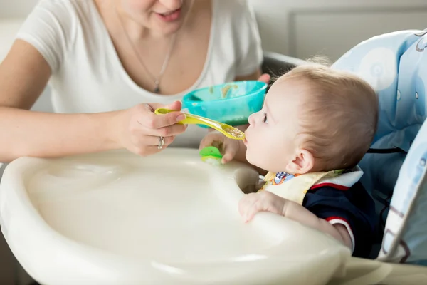 Bayi laki-laki lucu makan di kursi tinggi di dapur — Stok Foto