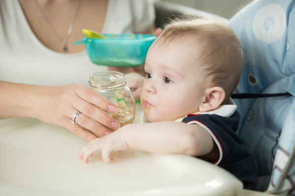Closeup of mother feeding baby boy with porridge