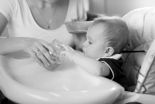Portrait of young mother feeding her baby on kitchen — Stock Photo, Image