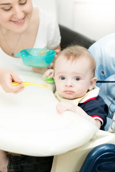 Young woman feeding her baby from spoon with apple sauce — Stock Photo, Image