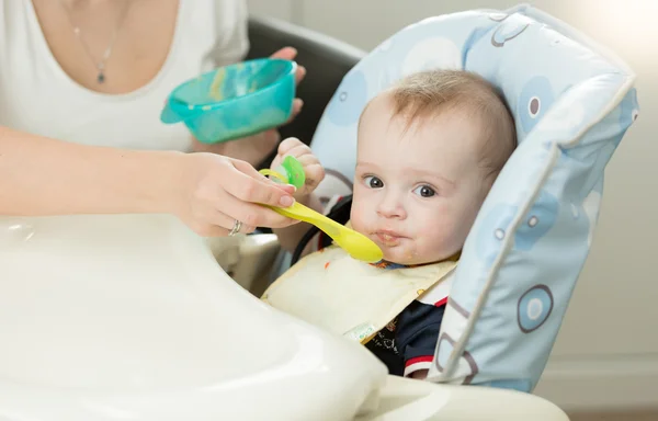 Primer plano de la madre joven alimentando al bebé en silla alta —  Fotos de Stock