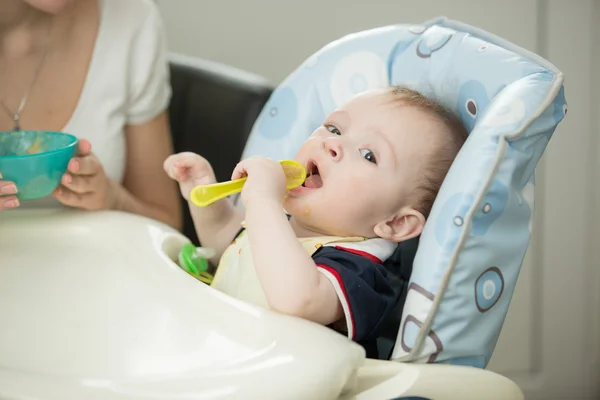 Baby playing with spoon while eating — Stock Photo, Image