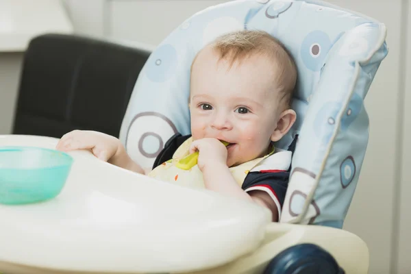 Retrato tonificado de bebé sonriente sentado en trona y comiendo g —  Fotos de Stock