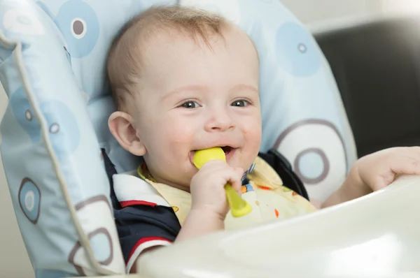 Hermoso niño de 9 meses jugando con cuchara mientras come —  Fotos de Stock