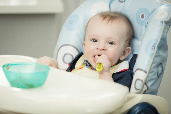Retrato de niño adorable de 9 meses comiendo en silla alta en el kit —  Fotos de Stock