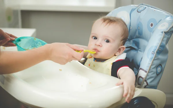 Retrato de niño sentado en trona en la cocina y comiendo de —  Fotos de Stock