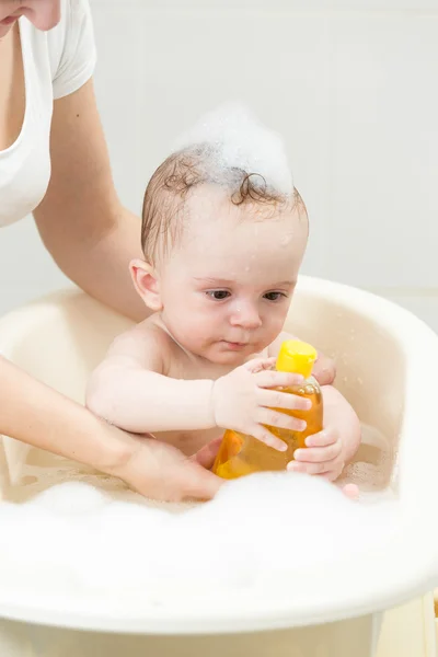 Портрет мальчика, принимающего ванну и держащего бутылочку шампуня — стоковое фото