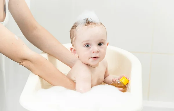 Madre bañando a su bebé en baño de plástico — Foto de Stock