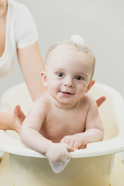 Lindo bebé sonriente sentado en el baño y mirando a la cámara — Foto de Stock